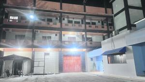 a lit up building with a red door at night at Braz Hotel in Tomé-Açu