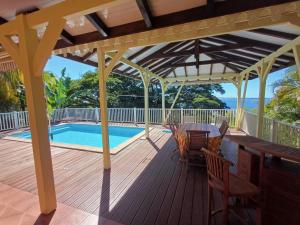 a wooden deck with a pool and a pergola at Villa Petitparadis in Le Carbet