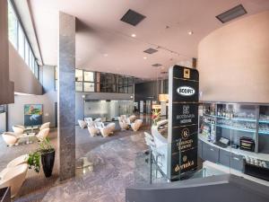eine Lobby mit einer Bar mit weißen Stühlen in der Unterkunft Hotel City Maribor in Maribor