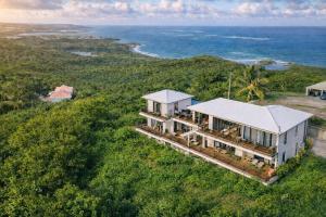 an aerial view of a house on a hill next to the ocean at Villa Vincent des Caps in Le Marin