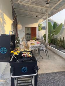a grill on a patio with a table and chairs at Jc Pran บ้านพัก in Sam Roi Yot