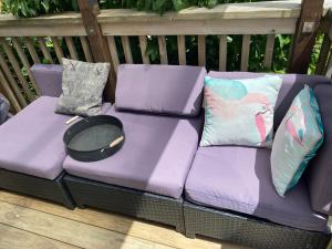 a purple couch sitting on a deck with pillows at Podgsters in Mangonui