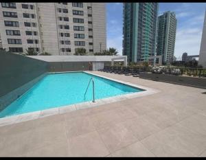 a large swimming pool in a city with tall buildings at Nómade Summer Home in Iquique