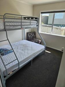 a bedroom with two bunk beds and a chair at Podgsters in Mangonui