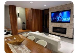 a living room with a table and a tv on a fireplace at Casa de luxo com piscina in Florianópolis