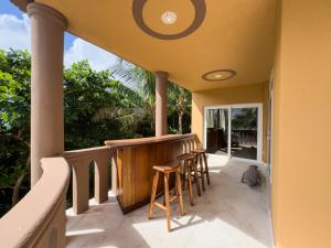 a porch with stools and a bar on a house at Belizean Cove Estates Beachfront Villas in San Pedro