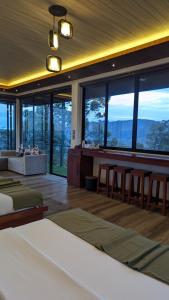 a bedroom with a bed and tables and windows at Nilowin Glenanore Guesthouse in Haputale