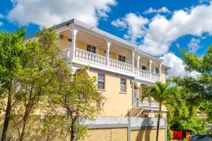 un edificio giallo con balcone bianco di Cozy Apartments And Car Rentals a Canefield