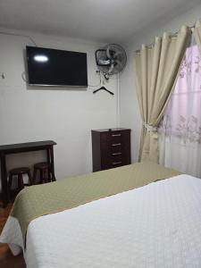 a bedroom with a bed and a flat screen tv on the wall at Andes Hostal Serena in La Serena