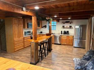 a kitchen with wooden cabinets and a bar with stools at Cozy Cabin near KentuckyLake in Murray +8 photos