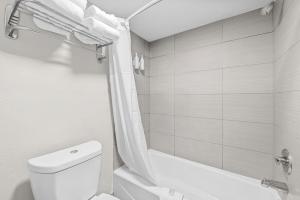 a white bathroom with a toilet and a shower at Days Inn by Wyndham Chesapeake in Chesapeake +23 photos