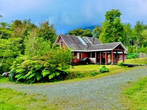 een rood huis met een grindweg ervoor bij Casa de campo Laguna escondida in Chaitén