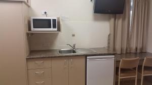 a small kitchen with a sink and a microwave at Injune Haven Motel in Injune
