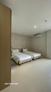 two beds in a room with white walls at The Perch Hostel in Olongapo