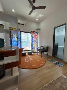 a living room with a ceiling fan and a rug at Sandbox in Malvan