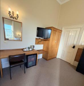 una stanza con una scrivania con una televisione e uno specchio di Campbell st Lodge a Castlemaine