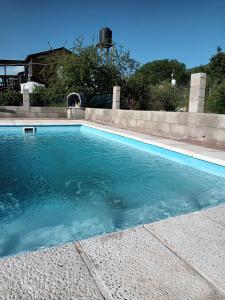 a swimming pool with blue water in a yard at Cabaña La Anita in Cosquín +9 photos