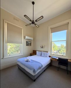 una camera da letto con un letto, una scrivania e due finestre di Campbell st Lodge a Castlemaine