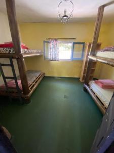 a room with three bunk beds and a green floor at Kuku hostel in Las Rabonas