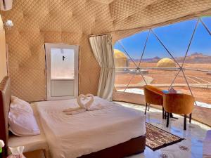 una camera da letto con un letto, una scrivania e una finestra di Desert calm a Wadi Rum