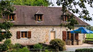 a brick house with a blue umbrella in front of it at Moulin gratia in Lay-Lamidou