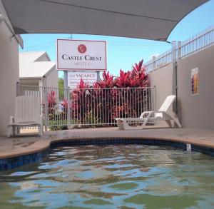 a swimming pool at a castle guest house with a sign at Castle Crest Motel in Townsville