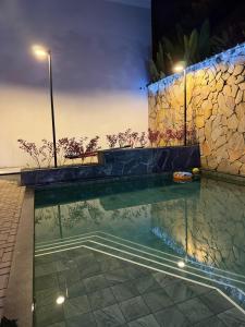 una piscina notturna con un muro di pietra di Apartamento novo e confortável, até 8 pessoas - Pague com cartão de crédito a Belém