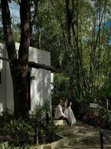 a bride and groom sitting on steps next to a tree at Baluarte Rest and Relaxation in Sampong +3 photos