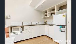 a kitchen with white cabinets and a white refrigerator at La Casita Preston Beach in Preston Beach