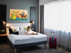 Una donna sdraiata su un letto in una stanza d'albergo di ibis styles Grudziadz a Grudziądz