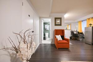 a living room with an orange chair and a vase of flowers at Vancouver UBC 2BD Suite in Vancouver