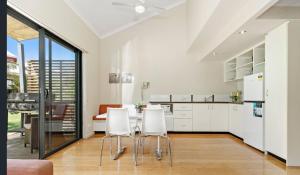 a kitchen with white cabinets and a table and chairs at La Casita Preston Beach in Preston Beach