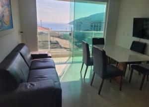 a living room with a couch and a table and a large window at Apartamento de 3 quartos com vista para o mar in Arraial do Cabo