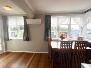 a dining room with a table and chairs and windows at A convenient stay in Hamilton