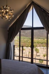 a bedroom with a large window looking out at the desert at OENO WINE LODGE Valle de Guadalupe in Valle de Guadalupe