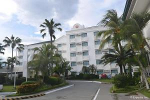 a large white building with palm trees in front of it at East Asia Royale Hotel in Lagao