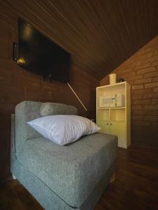 a couch with a pillow and a tv on the wall at Cabaña en Chachimbiro in Hacienda San Francisco