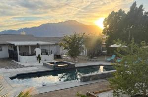 a house with a swimming pool with the sunset in the background at Casa Pueblo in Desert Hot Springs