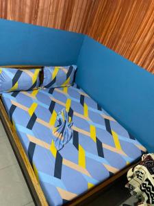 ein blaues Bett mit einer blau-gelben Bettdecke in der Unterkunft Le Centurion in Brazzaville + 12 Fotos