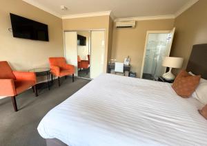 a hotel room with a large white bed and chairs at Sundowner Motel Hotel in Whyalla