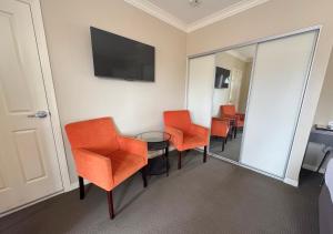 a room with orange chairs and a table and a mirror at Sundowner Motel Hotel in Whyalla +9 photos