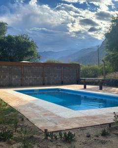 a swimming pool in a yard with a fence and mountains at Cabañas Pukara in Cafayate
