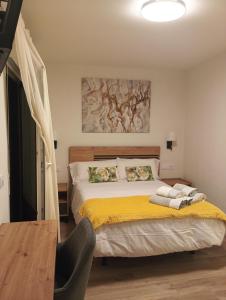 a bedroom with a bed with a yellow blanket at Alojamientos Centro Berzosa in Berzosa del Lozoya