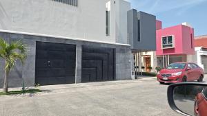 a red car parked next to a building with two garage doors at suites vergel terraza in Orizaba +1 photo