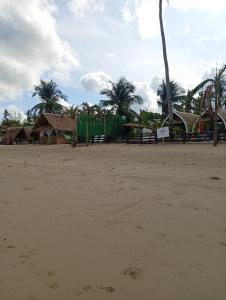 a sandy beach with houses and palm trees at El Hermosa Bice Camp in El Nido