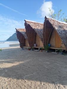 a resort with a thatched roof on the beach at El Hermosa Bice Camp in El Nido