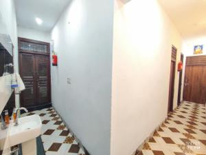 a bathroom with a white sink and a tiled floor at MK Devbhoomi Homestay in Kandikhal