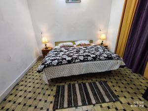 a bedroom with a bed and two lamps on two tables at MK Devbhoomi Homestay in Kandikhal