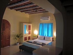 een slaapkamer met een bed en een raam met blauwe gordijnen bij Om Villa in Varkala