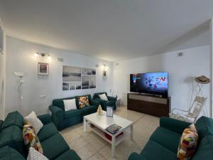 a living room with green couches and a tv at Vidamar in Abades
